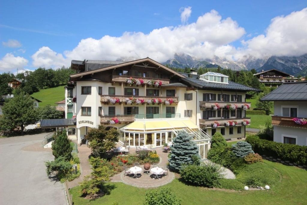 Una casa grande con un jardín enfrente. en Hotel Edelweiss, en Maria Alm am Steinernen Meer