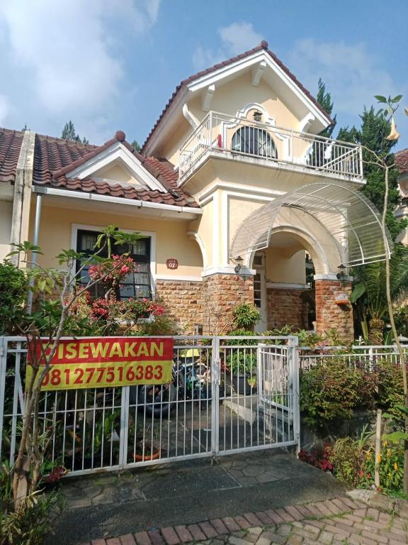 a house with a white gate with a balcony at Villa kota bunga cipanas 3 kamar baru in Cikundul