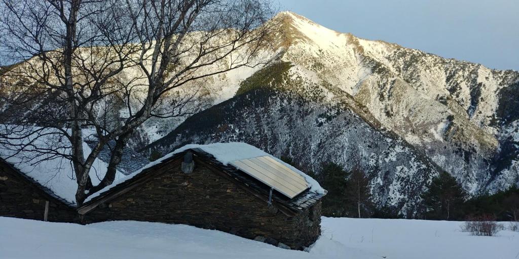 un techo cubierto de nieve de un edificio frente a una montaña en Bordes Pirineu, Costuix en Areu