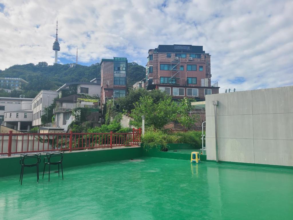 een zwembad van groen water met stoelen en gebouwen bij Well Plus Guest House in Seoul