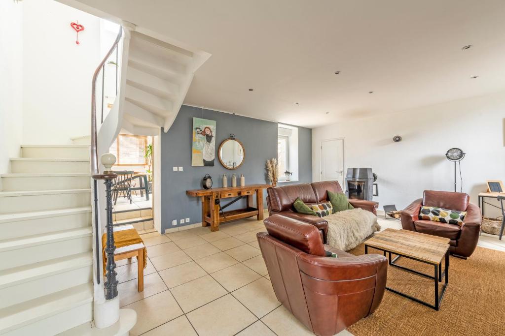 ein Wohnzimmer mit Ledermöbeln und einer Treppe in der Unterkunft Gîte Orloucie au coeur des Abers proche de tout in Lannilis