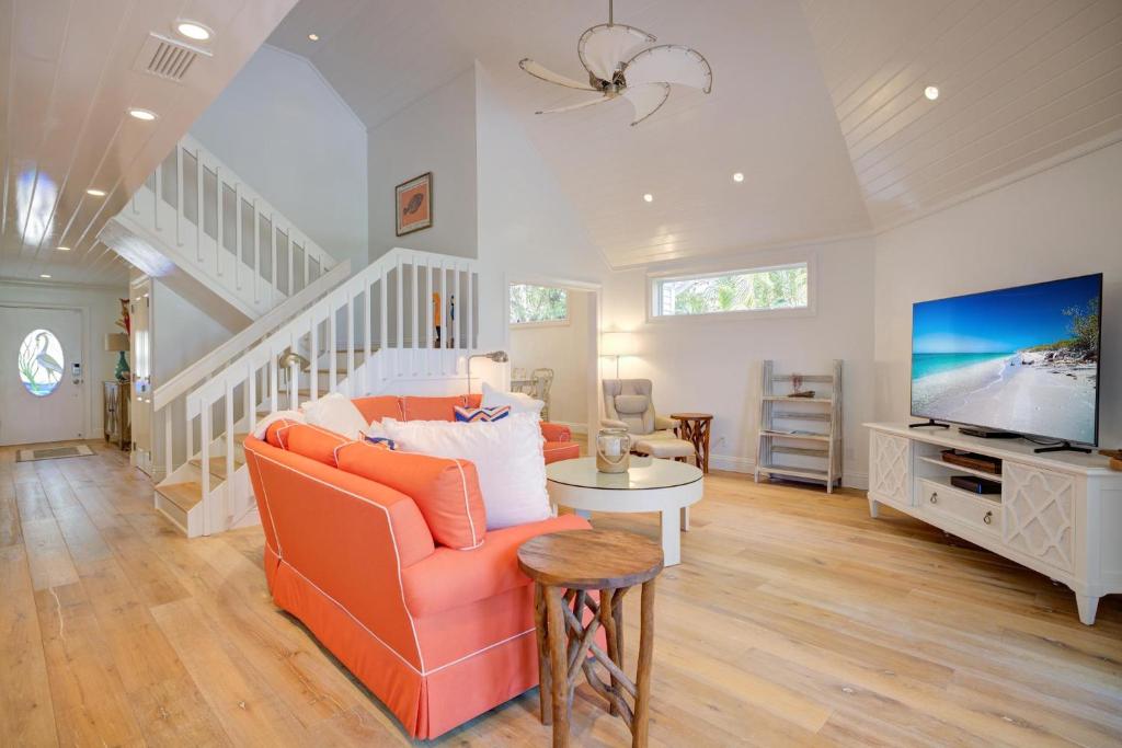 sala de estar con sofá naranja y TV en Sandals D, en Sanibel
