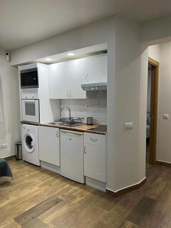 cocina con armarios blancos, lavadora y secadora en Portalegre, en Madrid