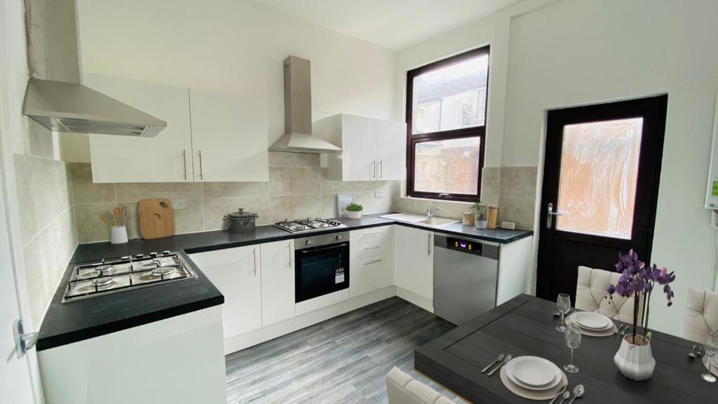 a kitchen with white cabinets and a stove top oven at The Aintree - By CHAPS in Aintree