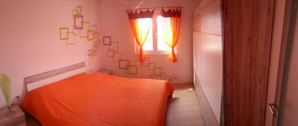 an orange bed in a room with a window at Apartment Tara in Sumartin
