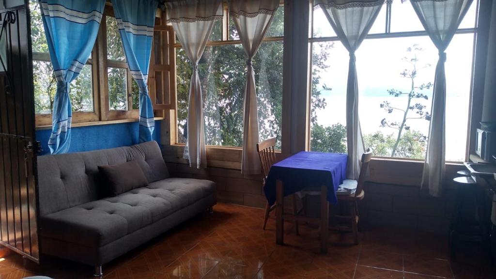 a living room with a couch and a table and windows at Cabaña Aurora in Zirahuén