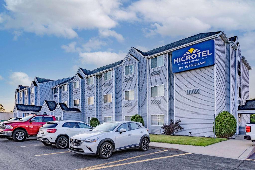 a hotel with two cars parked in a parking lot at Microtel Inn & Suites by Wyndham Plattsburgh in Plattsburgh