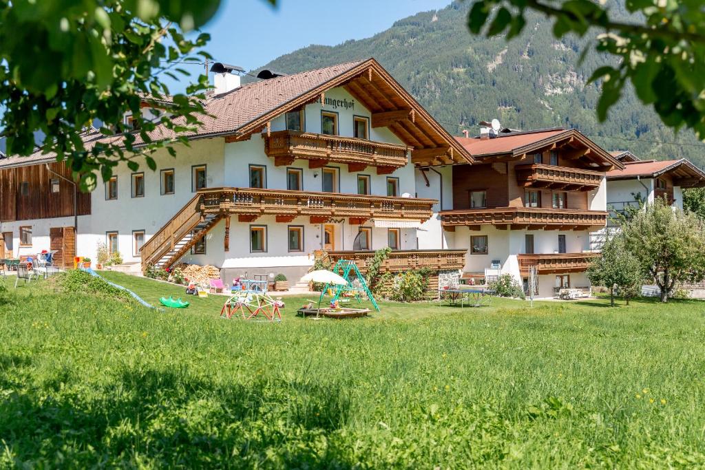 a large building with a grass field in front of it at Ferienwohnung Oberangerhof in Kaltenbach