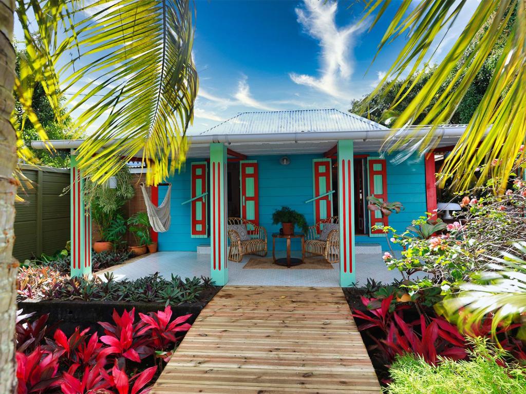 une maison bleue avec une passerelle en bois devant elle dans l'établissement L'incroyable maison de Mamie MECHANT, à Saint-Philippe