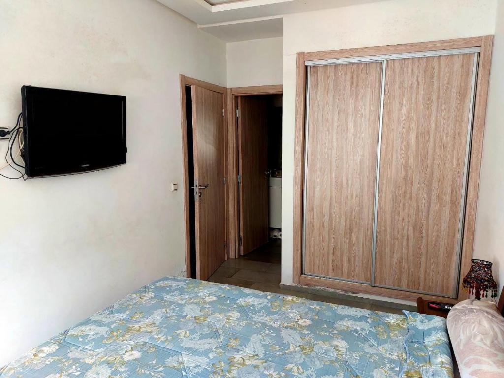 ein Schlafzimmer mit einem Bett und einem TV an der Wand in der Unterkunft Bouskoura, Joli appartement coup de cœur in Bouskoura