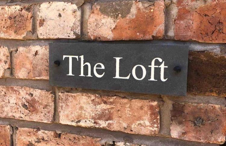 um sinal numa parede de tijolos que lê o loft em Private Loft Country Hideaway em Shifnal