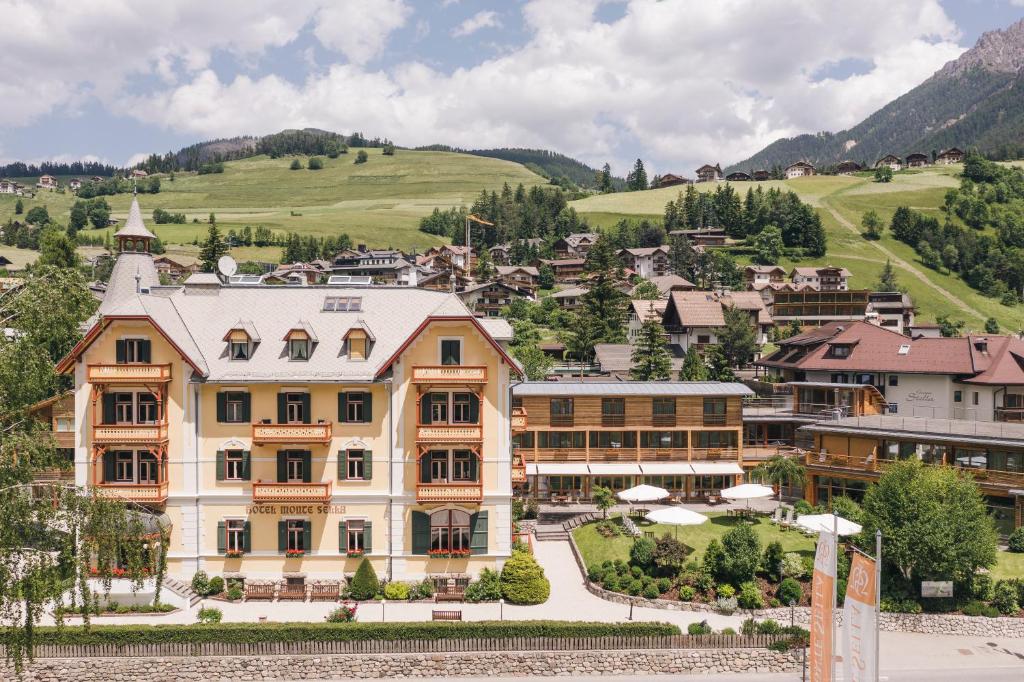 a large building in a town with mountains in the background at Hotel Monte Sella in San Vigilio Di Marebbe