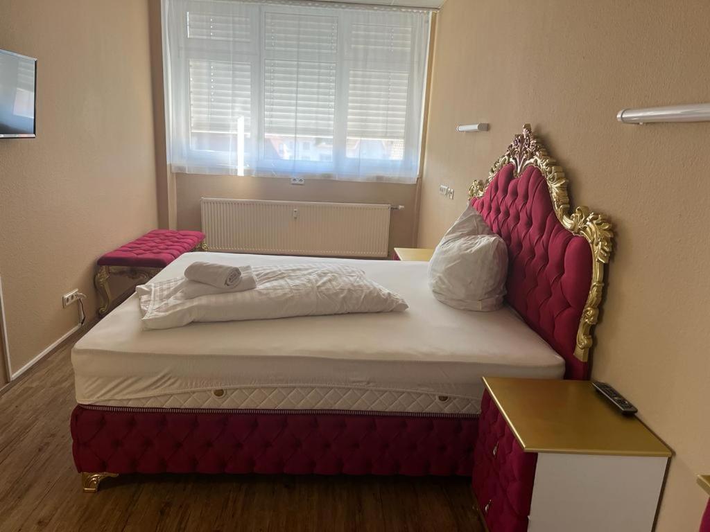 um quarto com uma cama com uma cabeceira vermelha e uma janela em Zimmer in Ramstein em Ramstein-Miesenbach