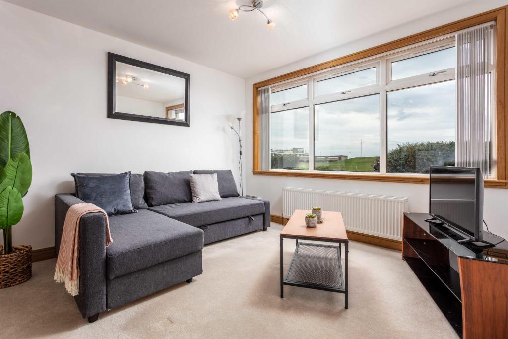 a living room with a couch and a television at West Sands - Donnini Apartments in Ayr