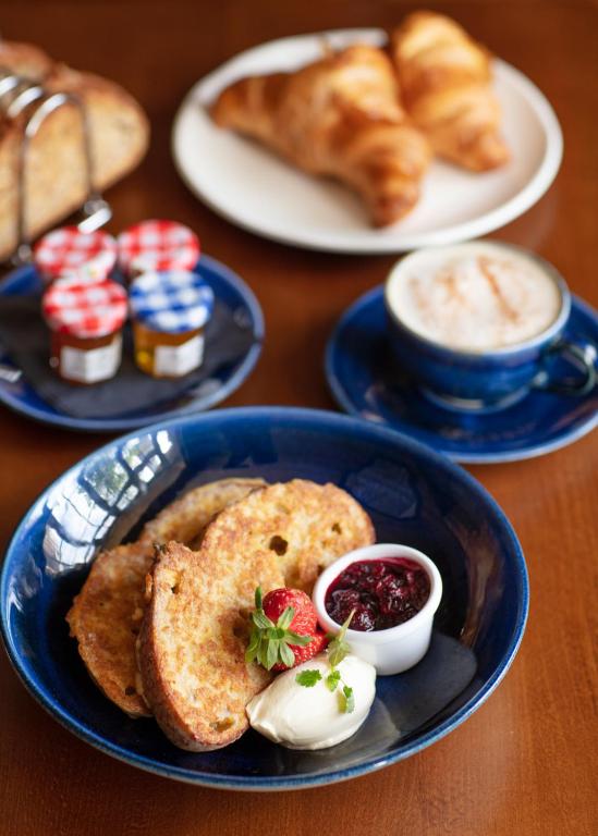 a table with plates of food with bread and pastries at The Whittling House in Alnmouth