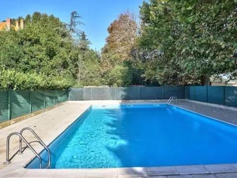 uma grande piscina azul com cerca e árvores em Vacances cosy avec piscine 1 à 4 pers dans joli appartement em Sérignan