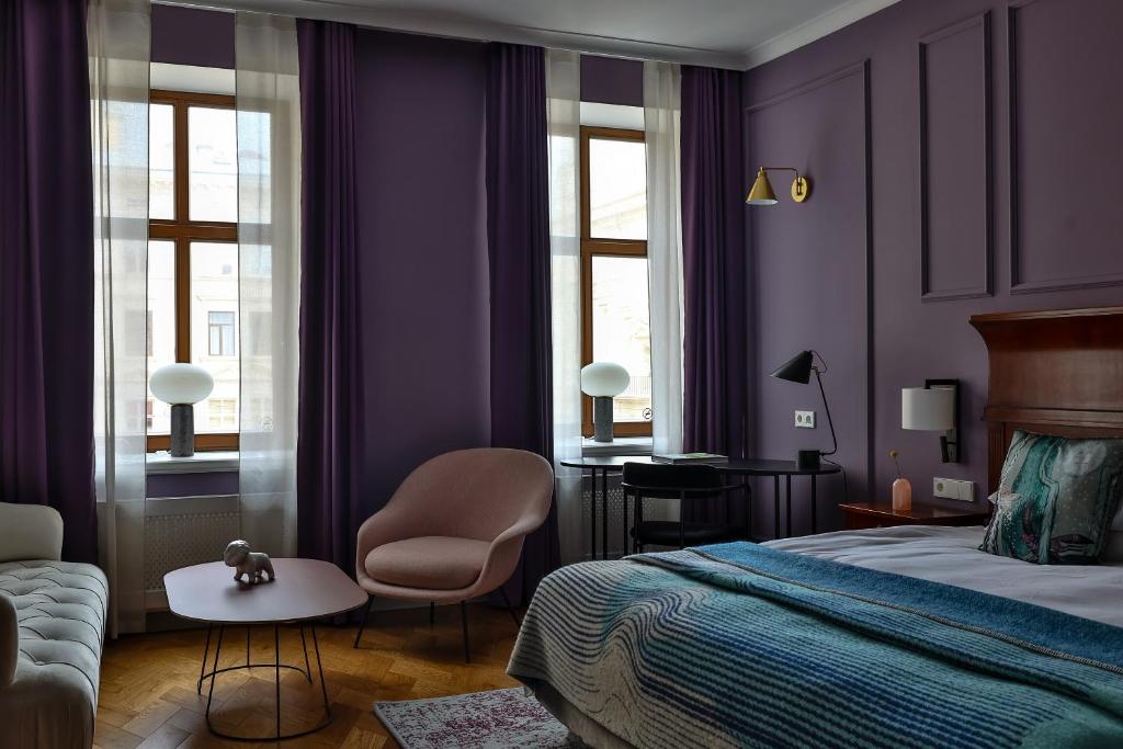 a bedroom with purple walls and a bed and a chair at Leopolis Hotel in Lviv