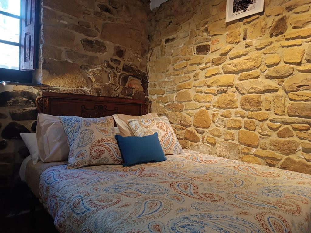 Cama en habitación con pared de piedra en La Castañar - La Vallicuerra Casas Rurales, en Mieres