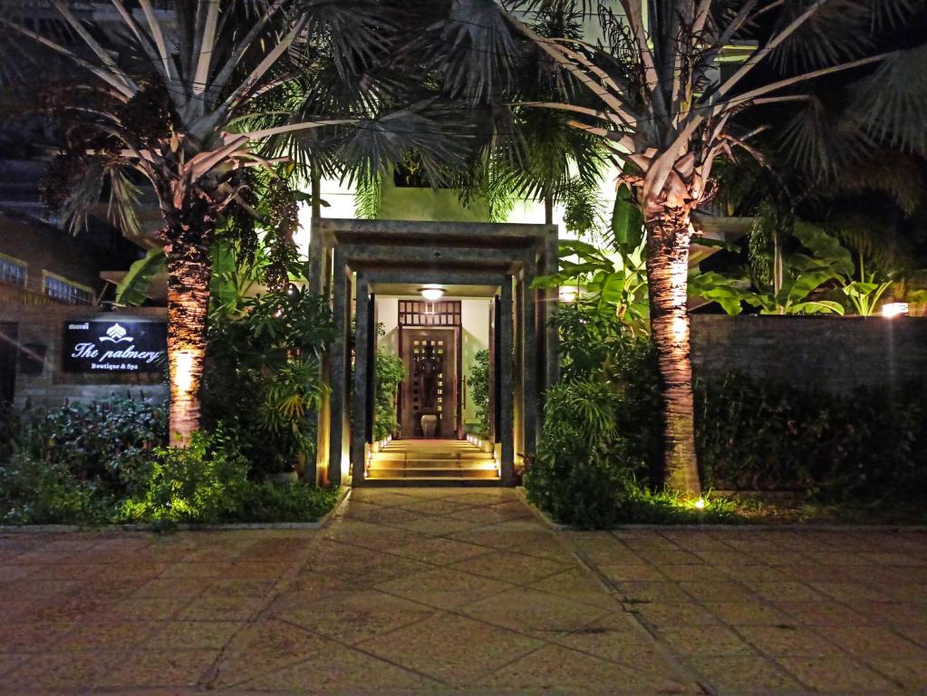 a hallway with a door between two palm trees at night at The Palmery in Siem Reap