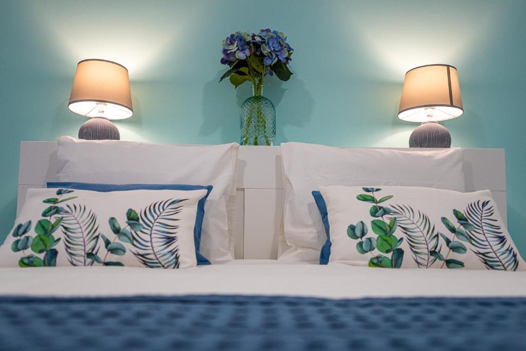 een bed met 2 lampen en een vaas met bloemen bij Dimore Italiane - Boutique Apartments in Corralejo