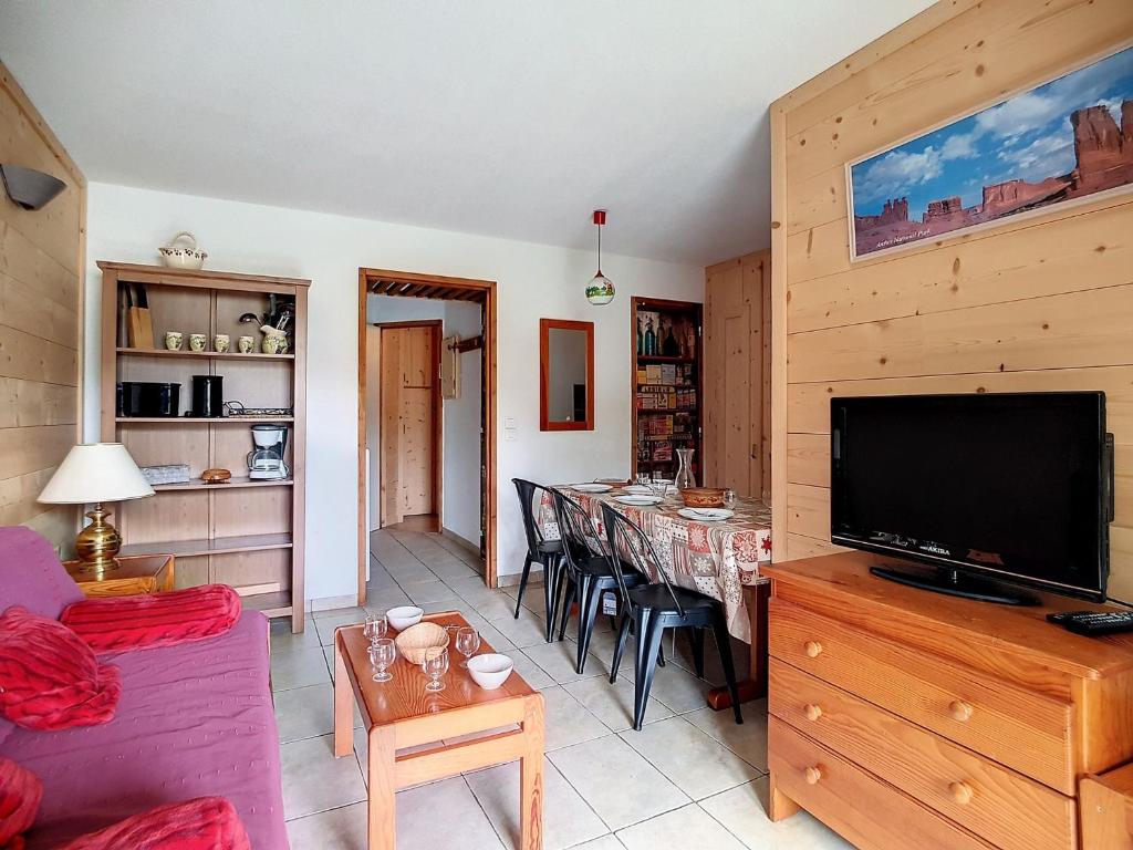 ein Wohnzimmer mit einem TV und einem Tisch mit Stühlen in der Unterkunft Appartement Les Menuires, 3 pièces, 6 personnes - FR-1-344-767 in Les Menuires