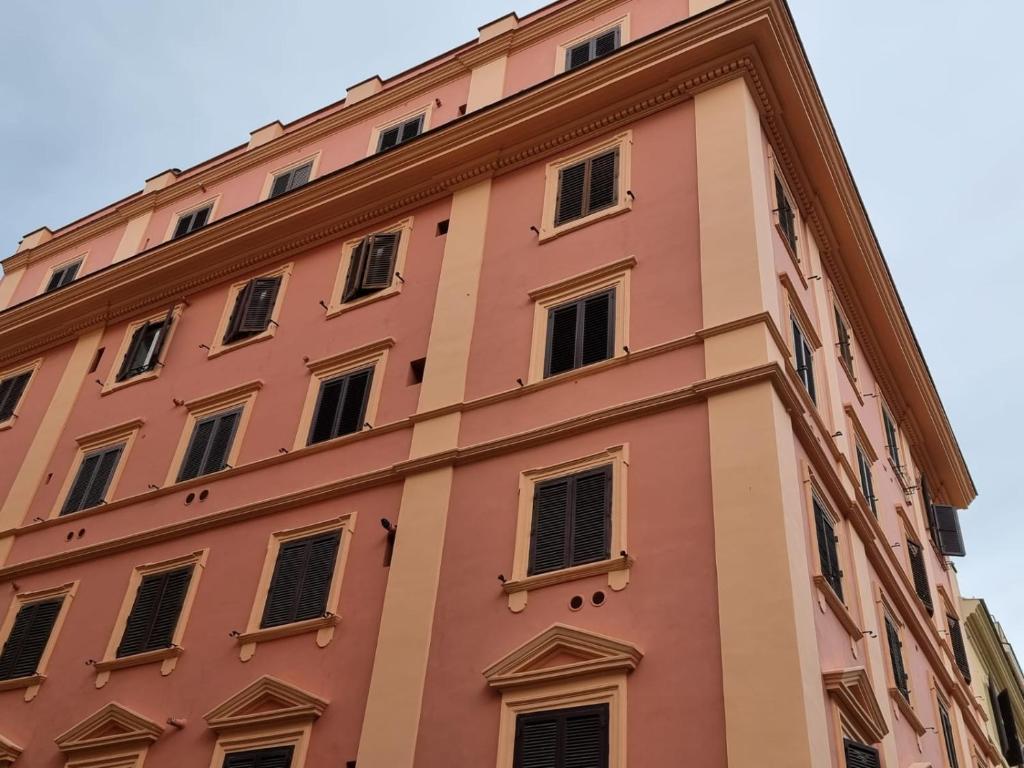 wysoki różowy budynek z wieloma oknami w obiekcie Colosseum 20 apartment w Rzymie