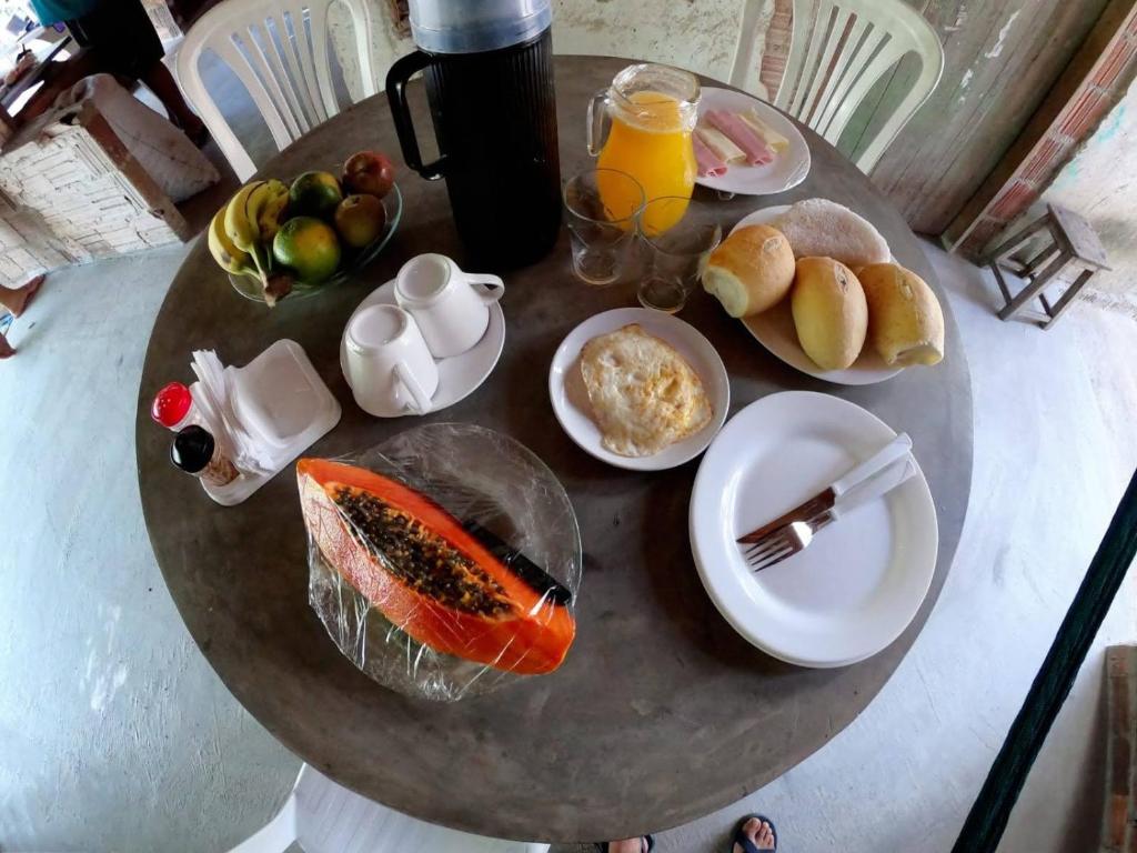 a table with breakfast foods and orange juice on it at Mila chalé in Cruz