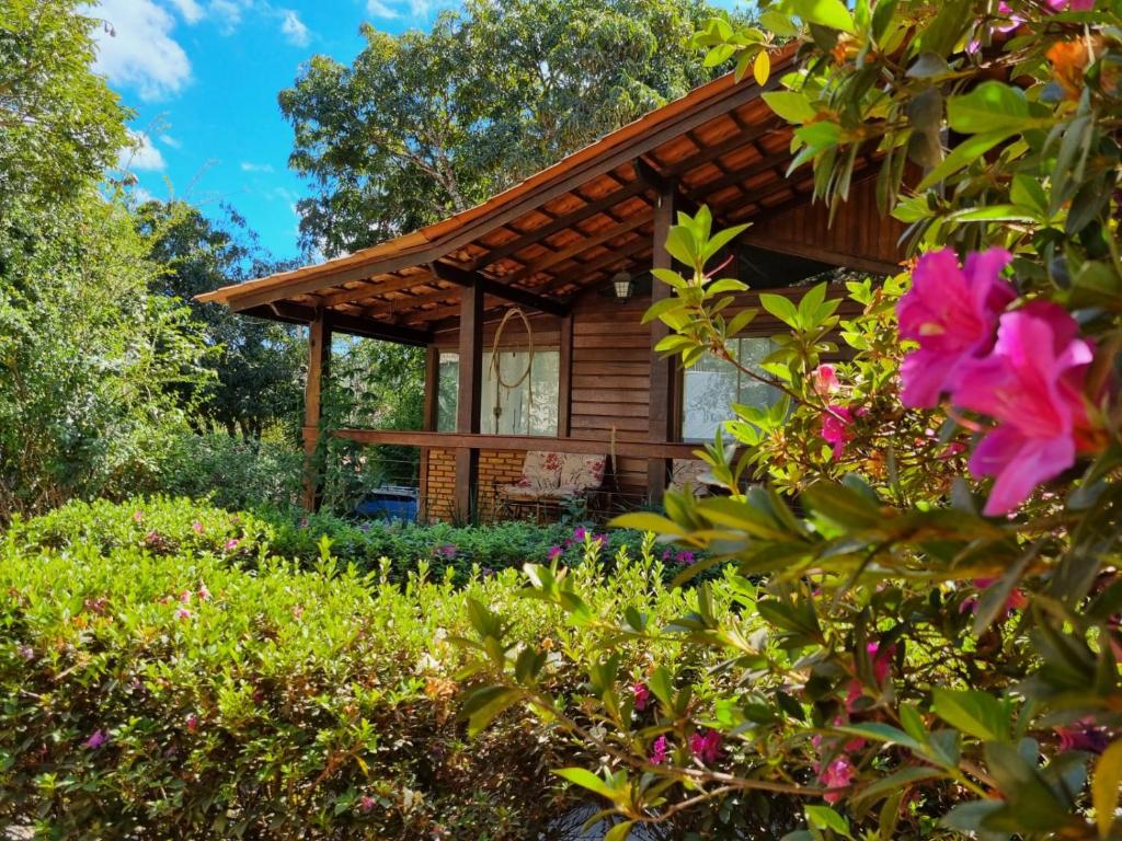 eine Blockhütte im Wald mit Blumen in der Unterkunft Casa 4 dorms 2 suites - localização perfeita no centrinho e rodeada de natureza in Alto Paraíso de Goiás