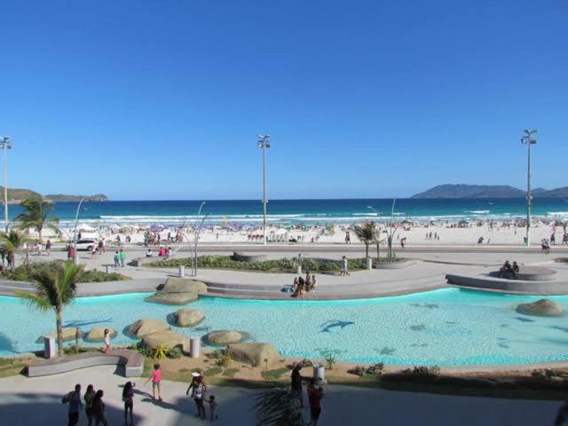 un groupe de personnes se tenant autour d'une piscine sur une plage dans l'établissement ECOSURF, à Cabo Frio