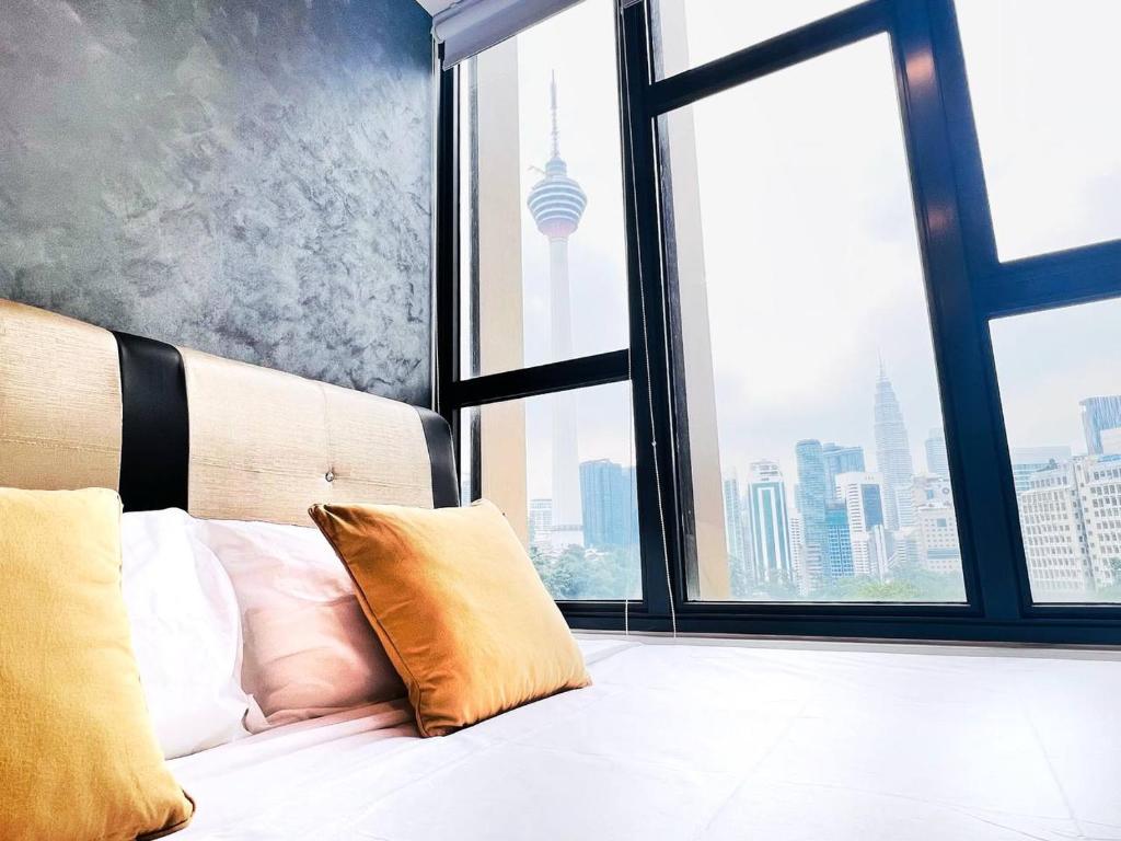 a bed with pillows in a room with a large window at KLCC View Grand Studio Suites ceylonz in Kuala Lumpur