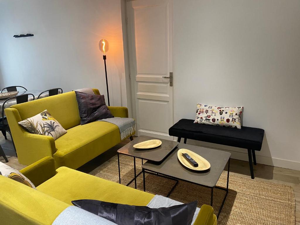 a living room with a yellow couch and tables at Le ker Maclow in Saint Malo