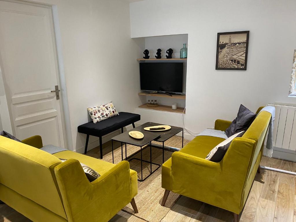 sala de estar con sillas amarillas y TV de pantalla plana en Le ker Maclow en Saint-Malo