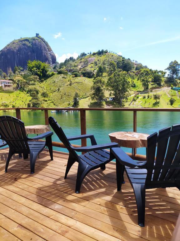 trois chaises et une table sur une terrasse avec vue sur l'eau dans l'établissement Ecolodge Bahia del Peñón, à Guatapé
