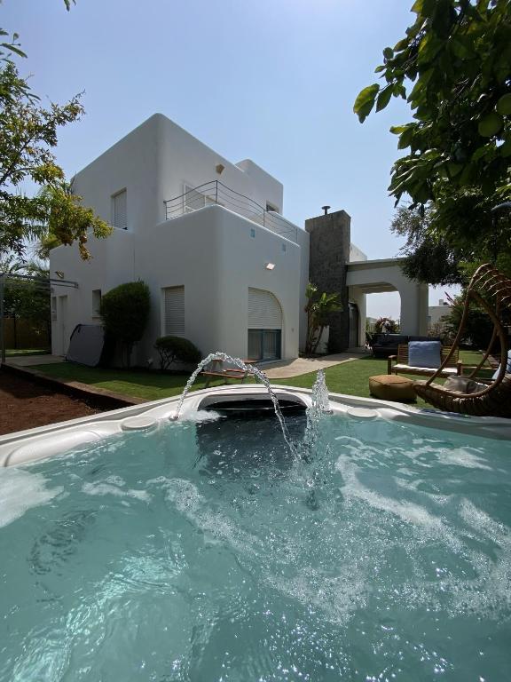 a swimming pool with a fountain in front of a house at Nirvana Maayan Baruh in Ma‘yan Barukh
