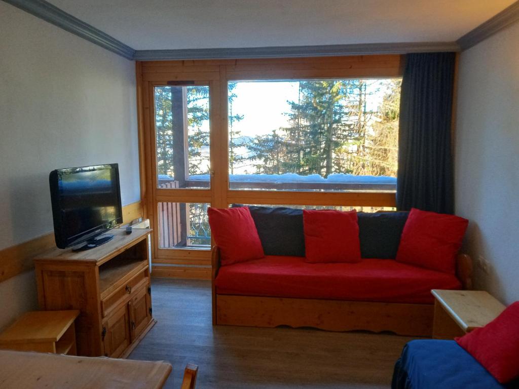 a living room with a red couch in front of a window at Appartement Le Thuria in Arc 1800