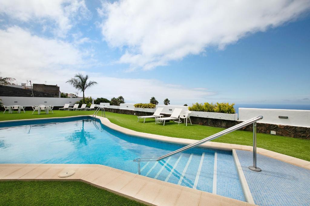 a swimming pool with chairs and the ocean in the background at Linaje del Pago Castellana in Tacoronte