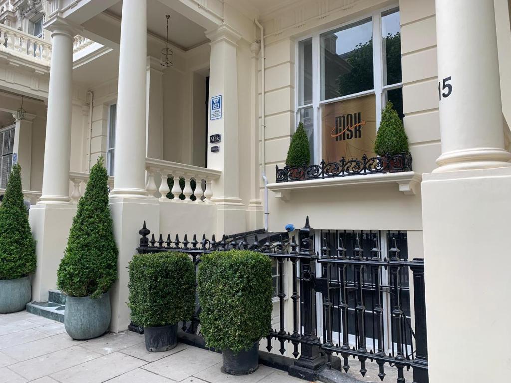 une maison blanche avec une clôture noire et des buissons dans l'établissement MSK Elite, à Londres
