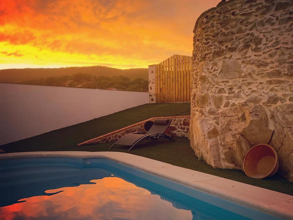 a swimming pool on the side of a building with a sunset at Casa Rural Sierra Tórtola 2 in Hinojales