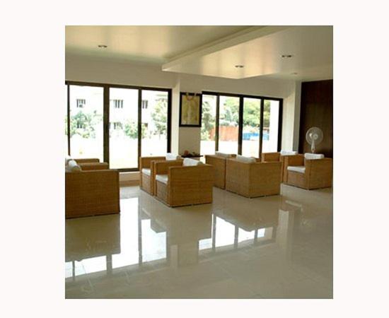 a living room with couches and tables and windows at ASR Guesthouse in Tirupati