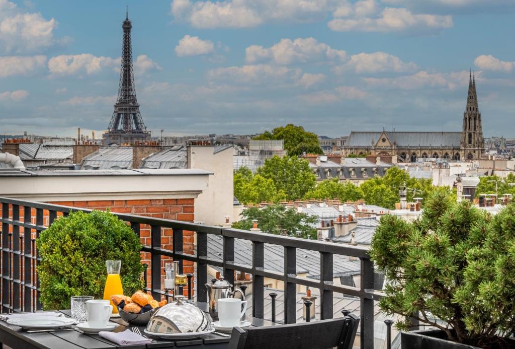a table on a balcony with a view of the eiffel tower at Hôtel Pont Royal Paris in Paris