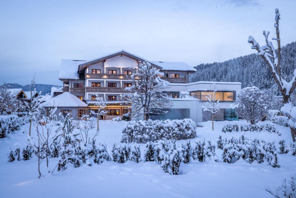 a building covered in snow with a garden in front at Superior Hotel Alpenhof in Flachau