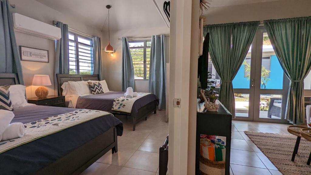 een slaapkamer met 2 bedden en een woonkamer bij Villas at Chalet De Buye in Cabo Rojo