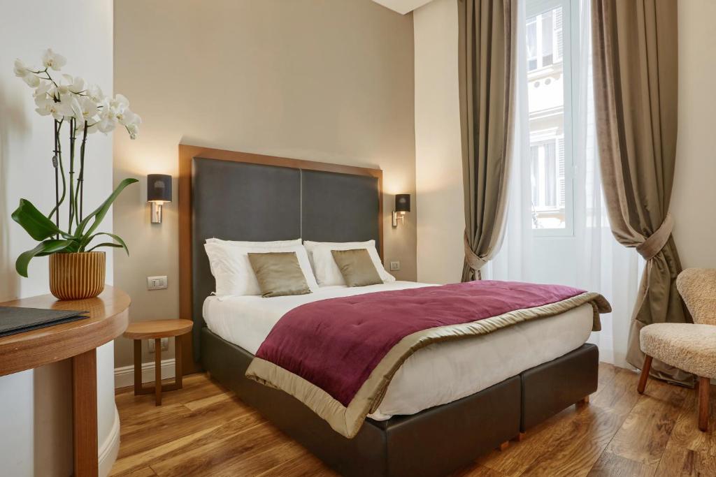 ローマにあるL'obelisque maison de luxeの大きなベッドとデスクが備わるホテルルームです。