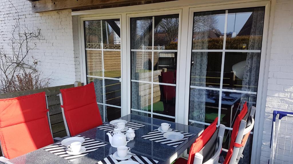 einen Tisch und Stühle auf einer Terrasse mit Glastüren in der Unterkunft Ferienwohnungen Brasse in Dornumersiel