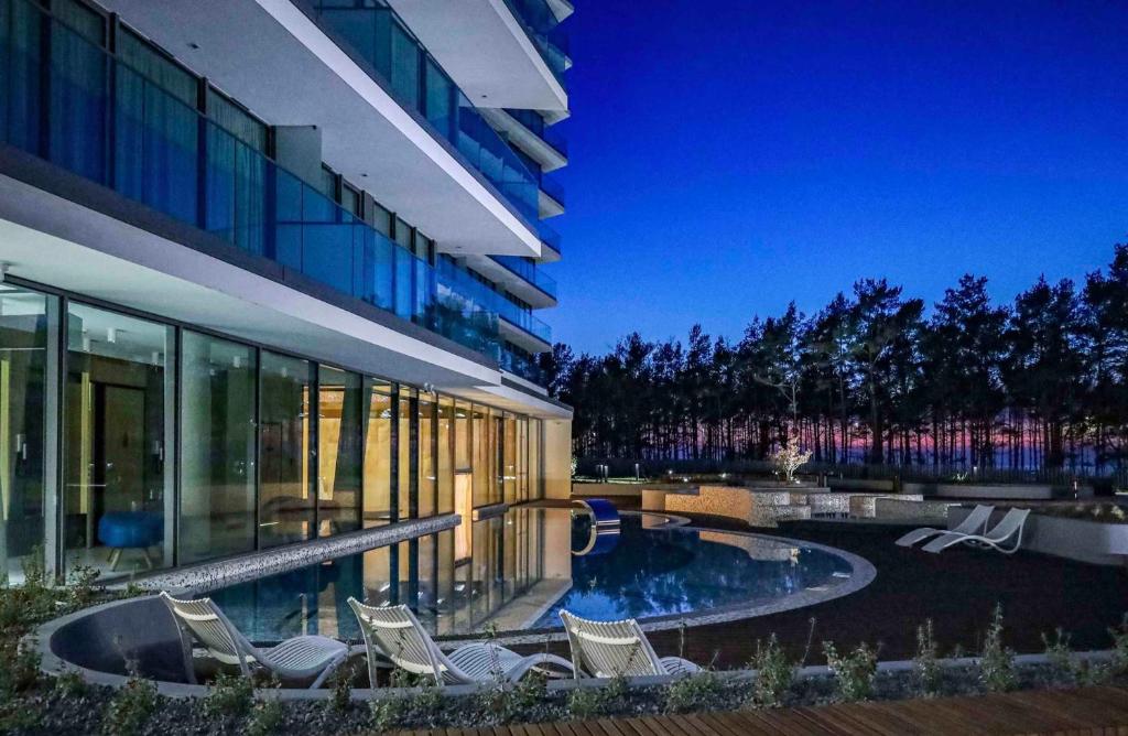 a building with a pool and chairs in front of it at Wave Międzyzdroje Resort & SPA in Międzyzdroje