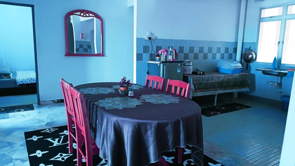 a blue room with a table with pink chairs at Cocobay Resort Cosy Apartment in Kampong Tanah Merah