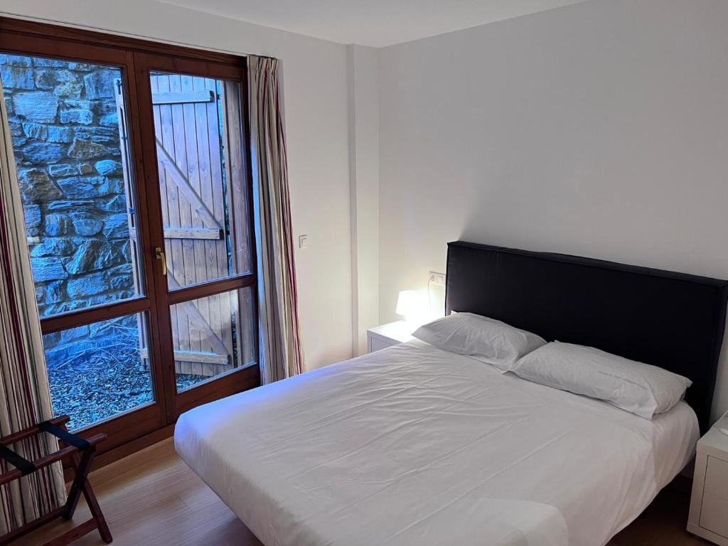 a bedroom with a bed and a large window at Pleta 214 in Soldeu