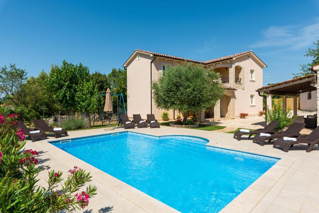 a swimming pool with chairs and a house at Beautiful villa Natura with pool in Labin in Labin