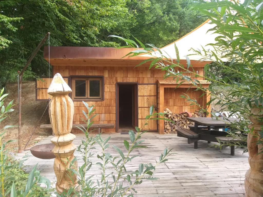 um pequeno barracão de madeira com uma mesa e um banco em La Grenouillette em Mirwart