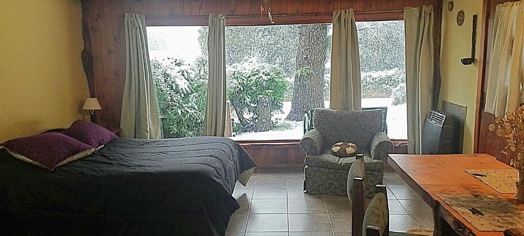 um quarto com uma cama, uma cadeira e uma janela em Cabaña en el bosque em San Carlos de Bariloche
